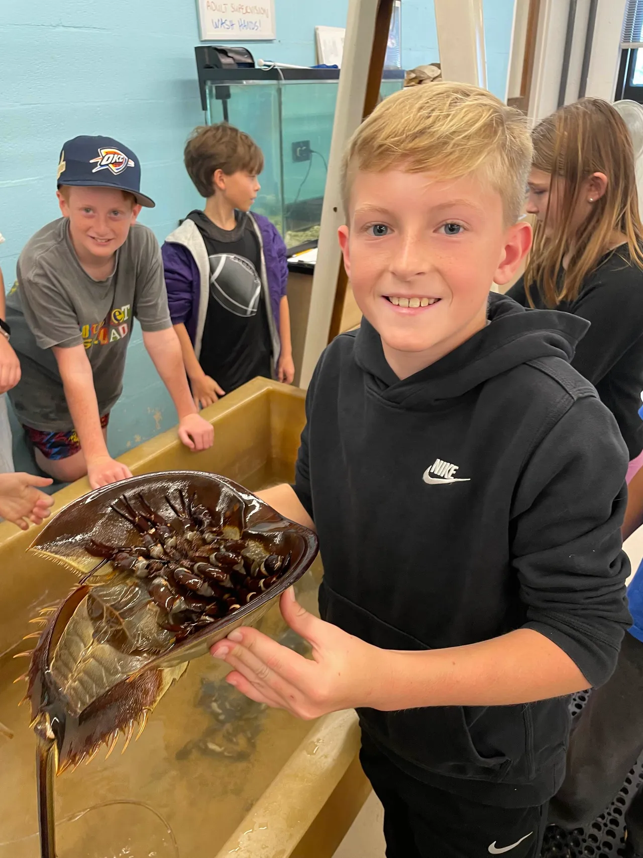 A male student shows off an item he discovered in an aquarium tank during a field trip