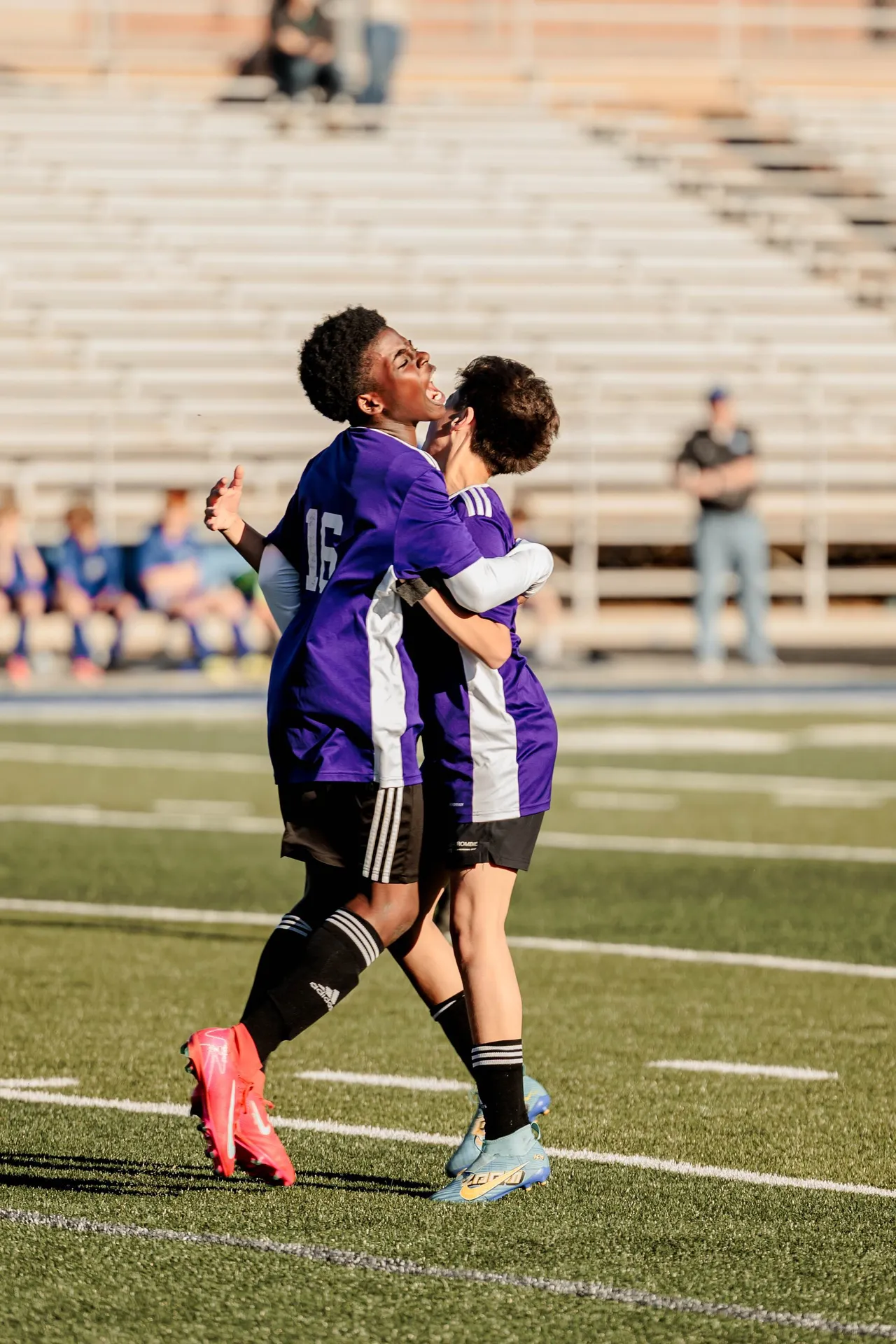 Two male middle school students hug and celebrate on the soccer field after a goal was scored