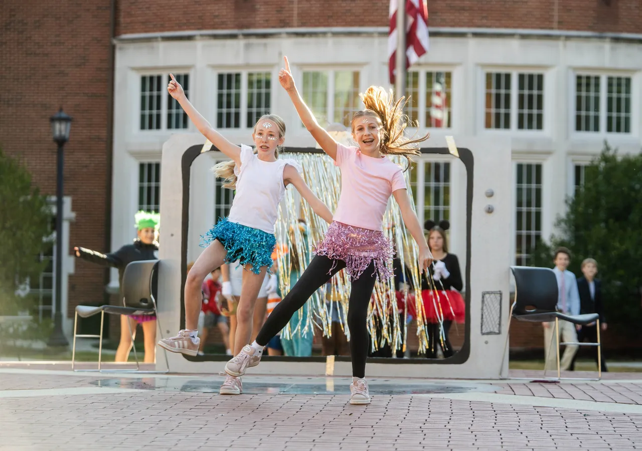 Two female middle school students sing and dance during an advisory skit at the annual Halloween event