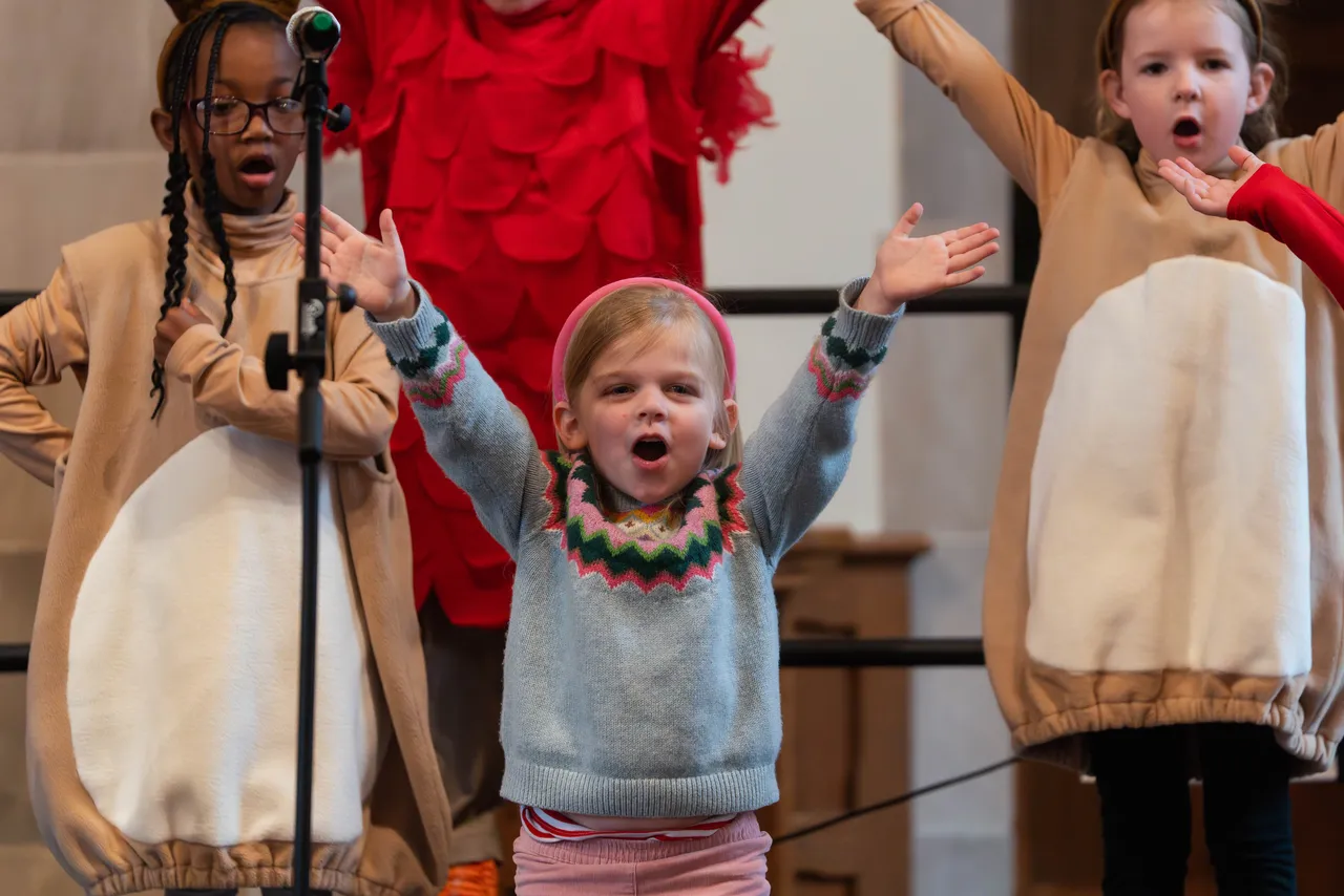 Three female primary grades students sing while performing in their class play during the holidays