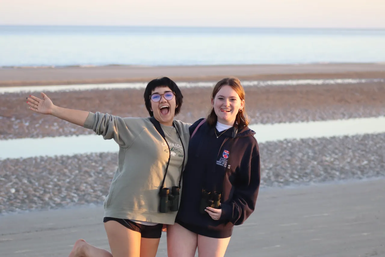 Two female high school girls on the beach during a birdwatching trip with their Zoology class