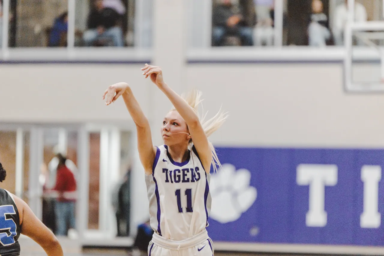 A female high school basketball player shoots the ball toward the basket