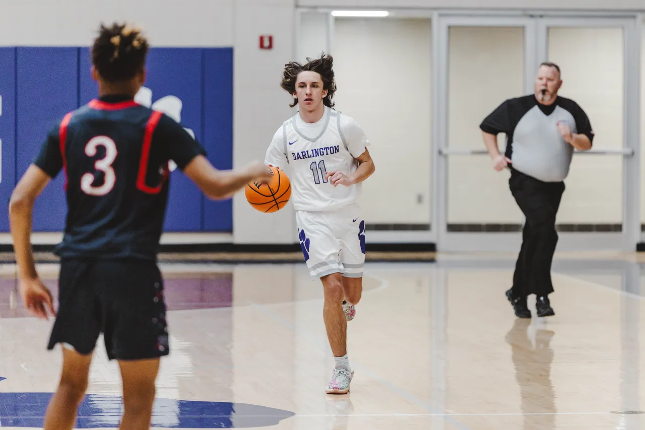 Male high school basketball player dribbles the ball down the court during a game