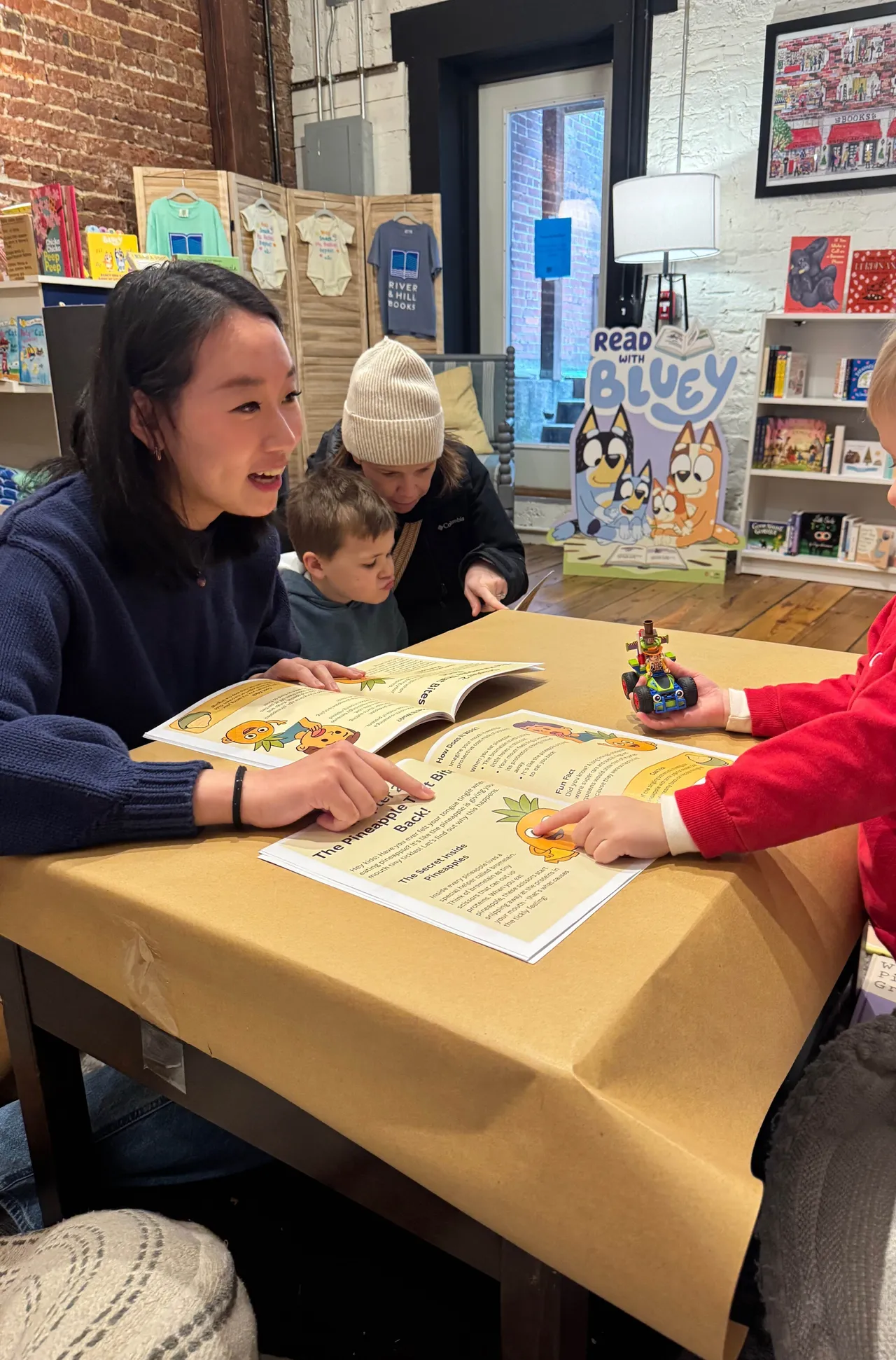 Female high school student reads a book she authored to younger students