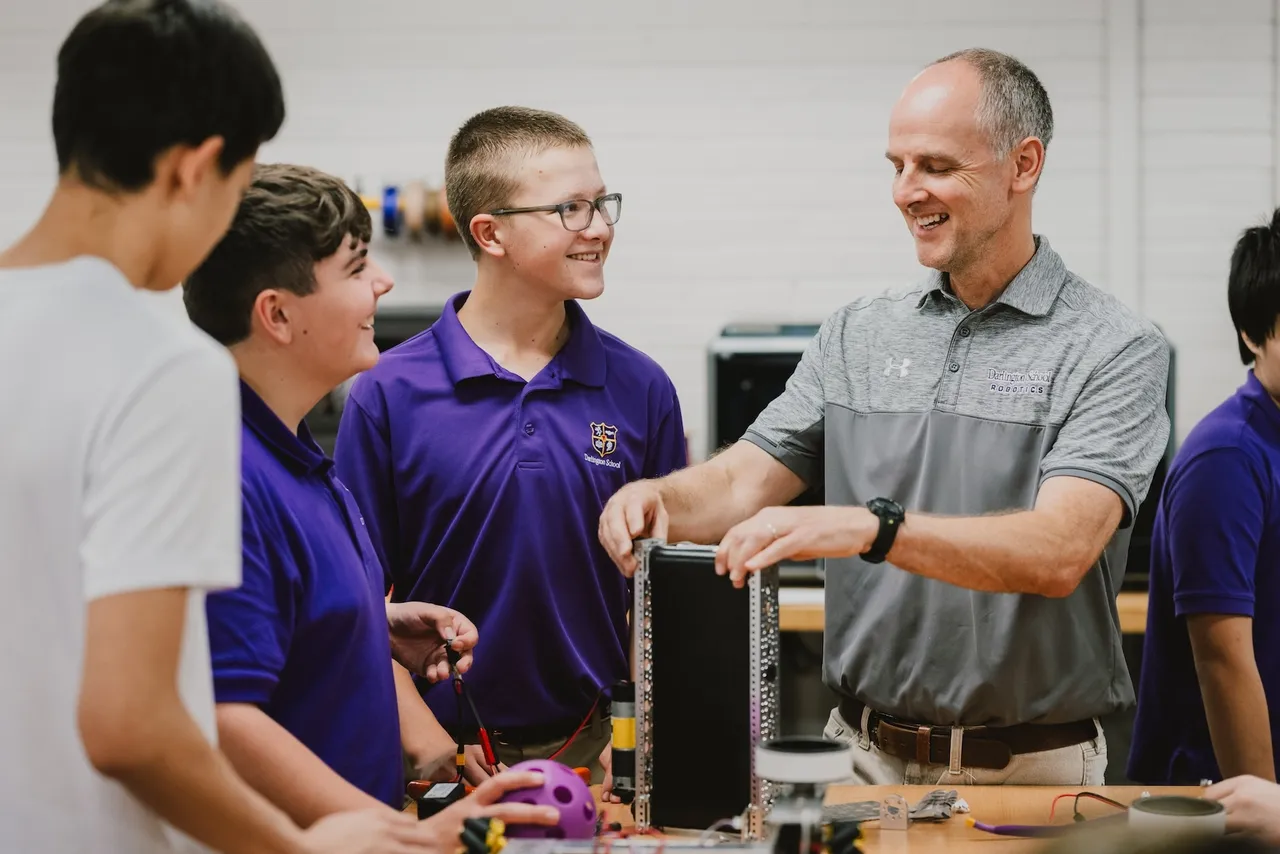 Upper school science teacher works with a group of boys in the makerspace