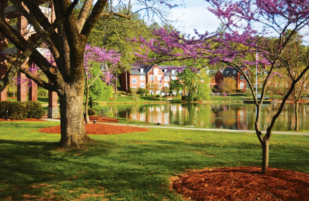 Silver Lake reflects campus buildings and blooming trees on Darlington School's campus.