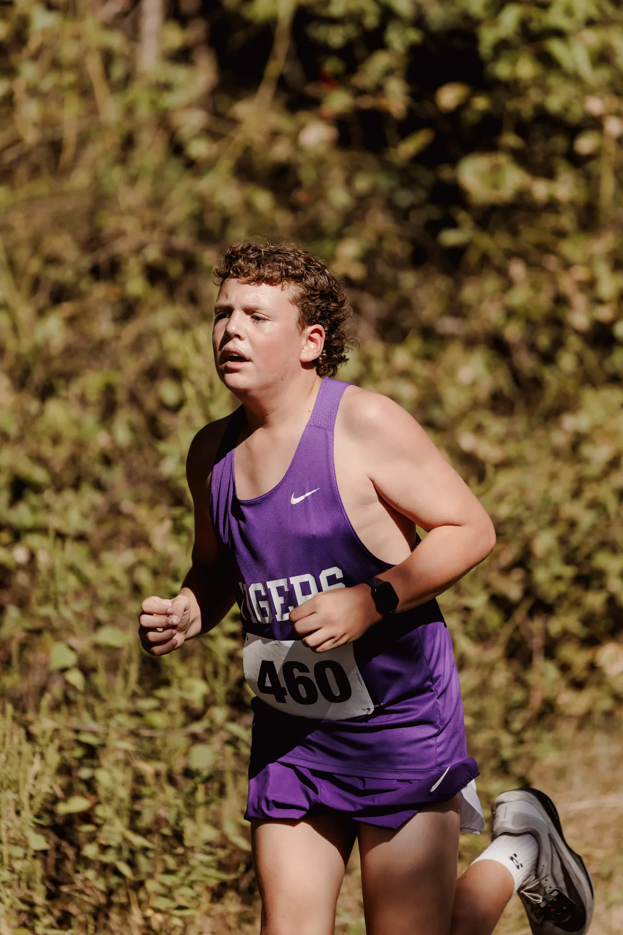 A male middle school cross country runner competes during a race.