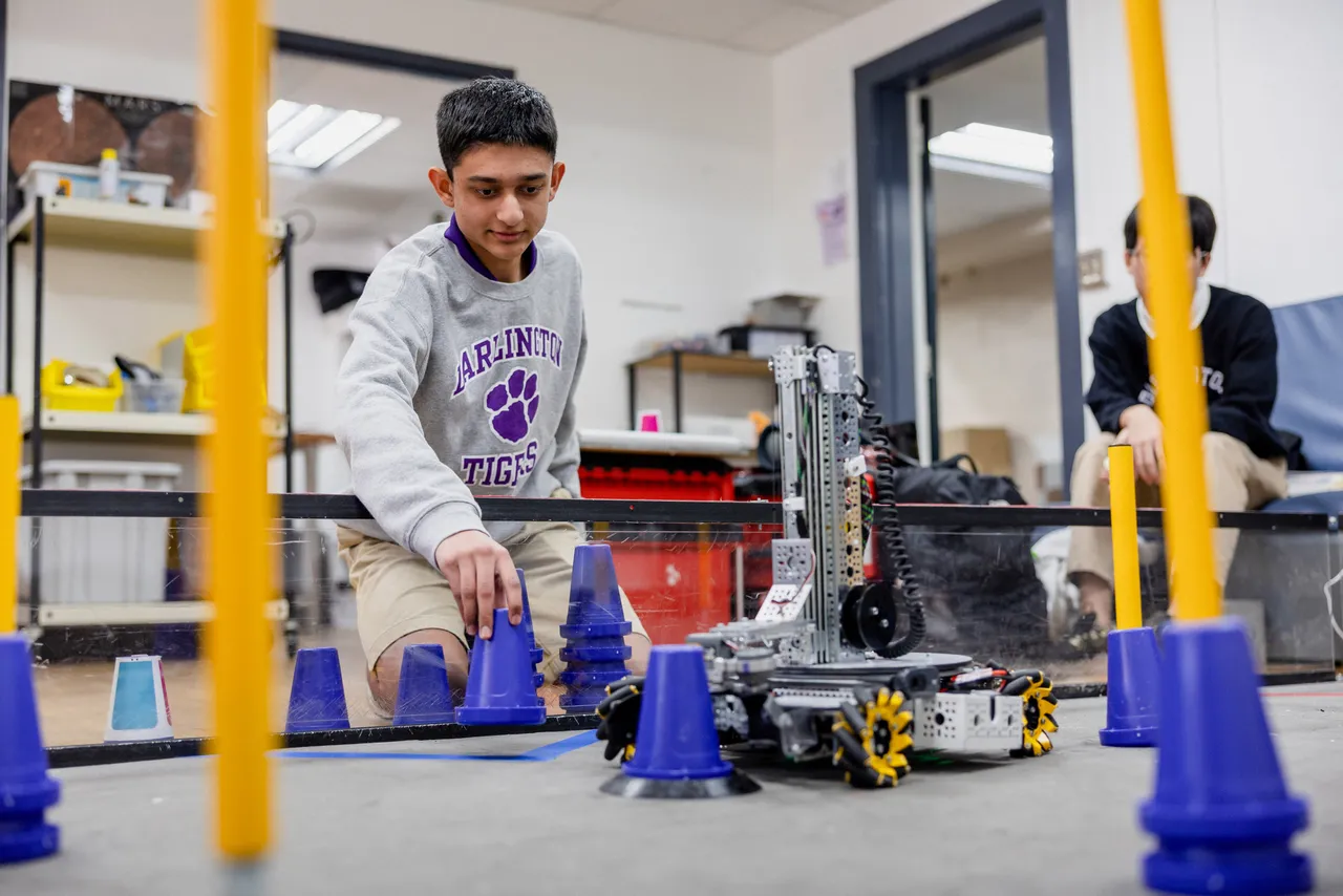Male high school student works with a robot in the makerspace