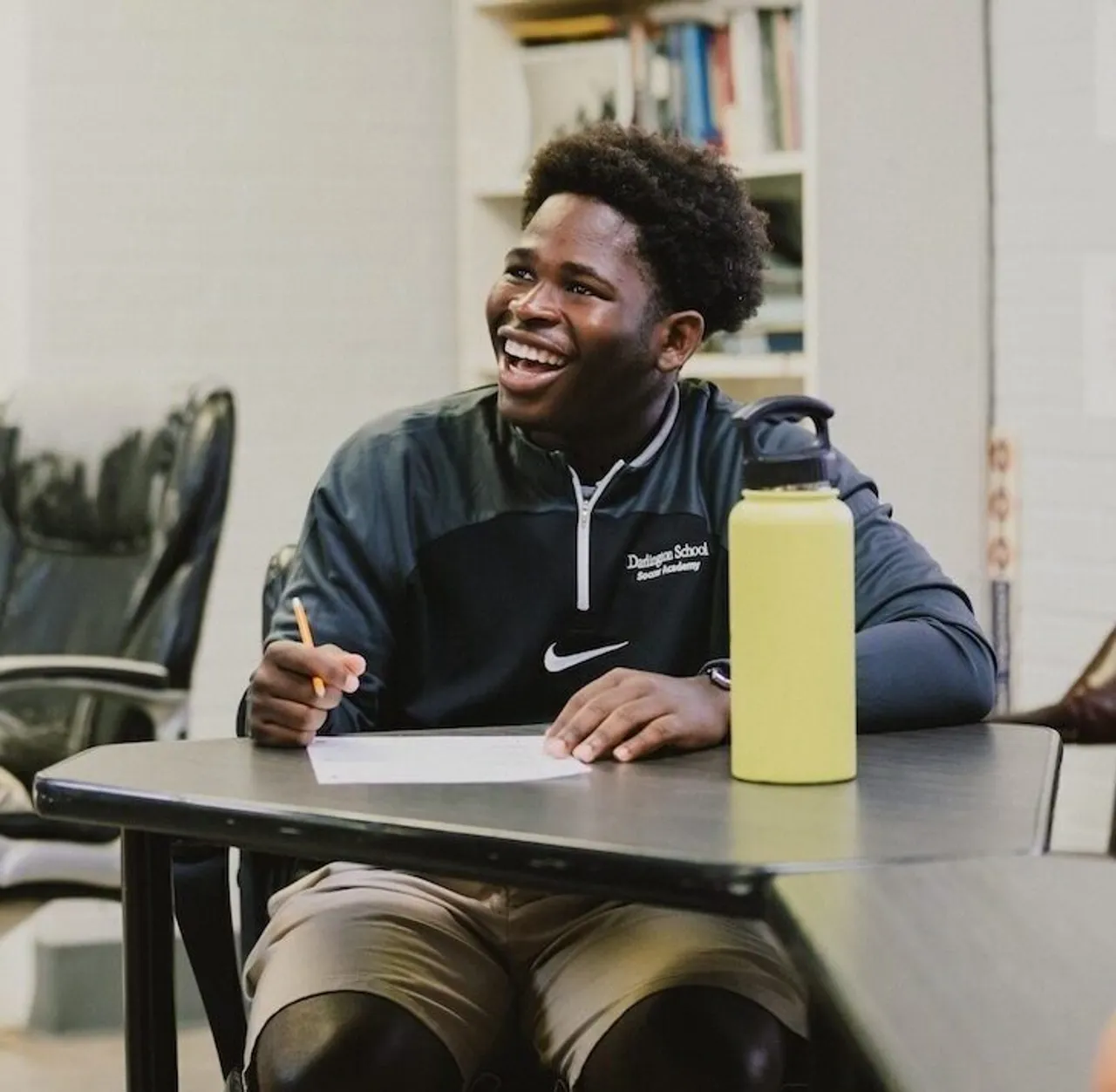 Male high school student smiles at his desk in English class