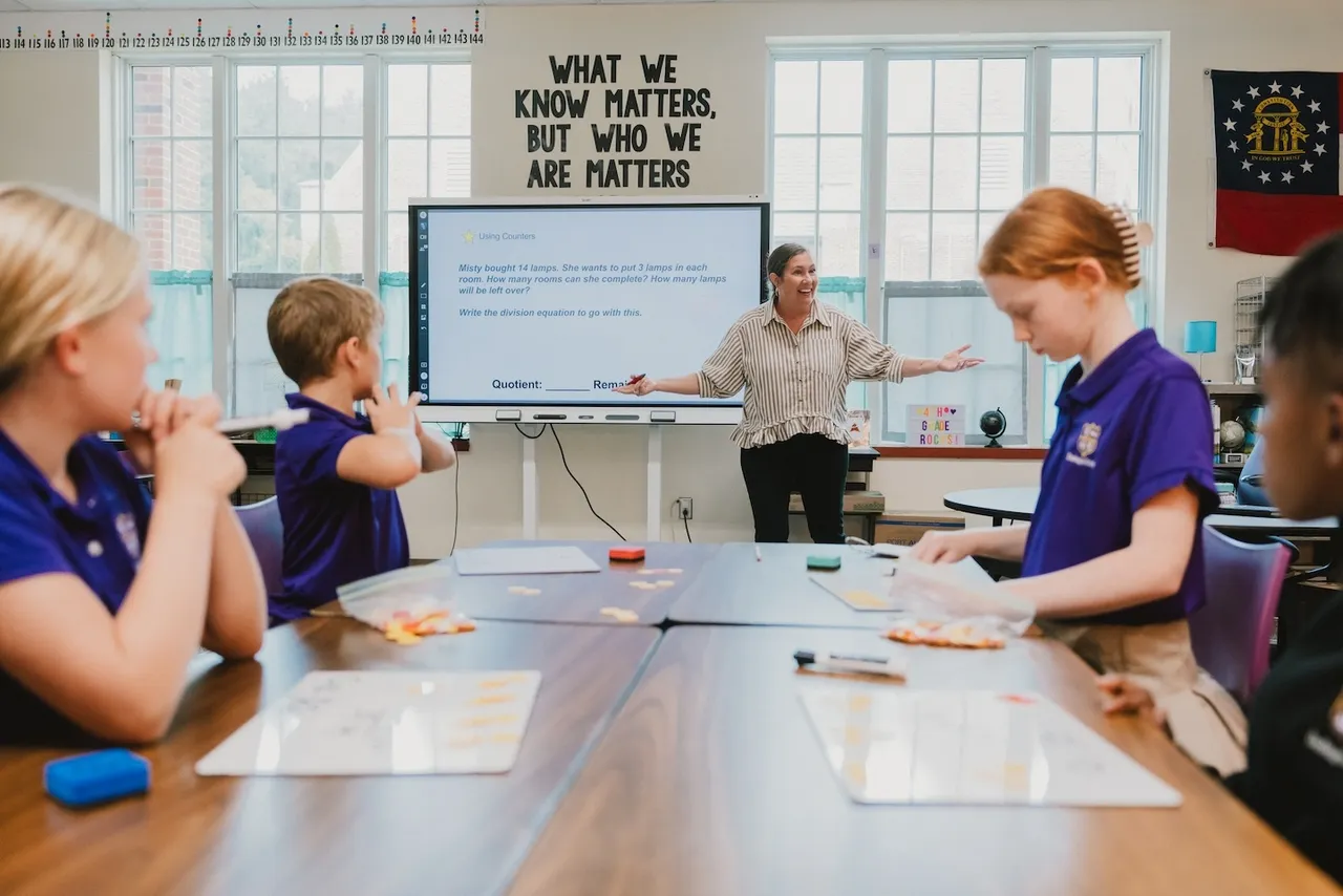 Female teacher stands in front of classroom of engaged students teaching math