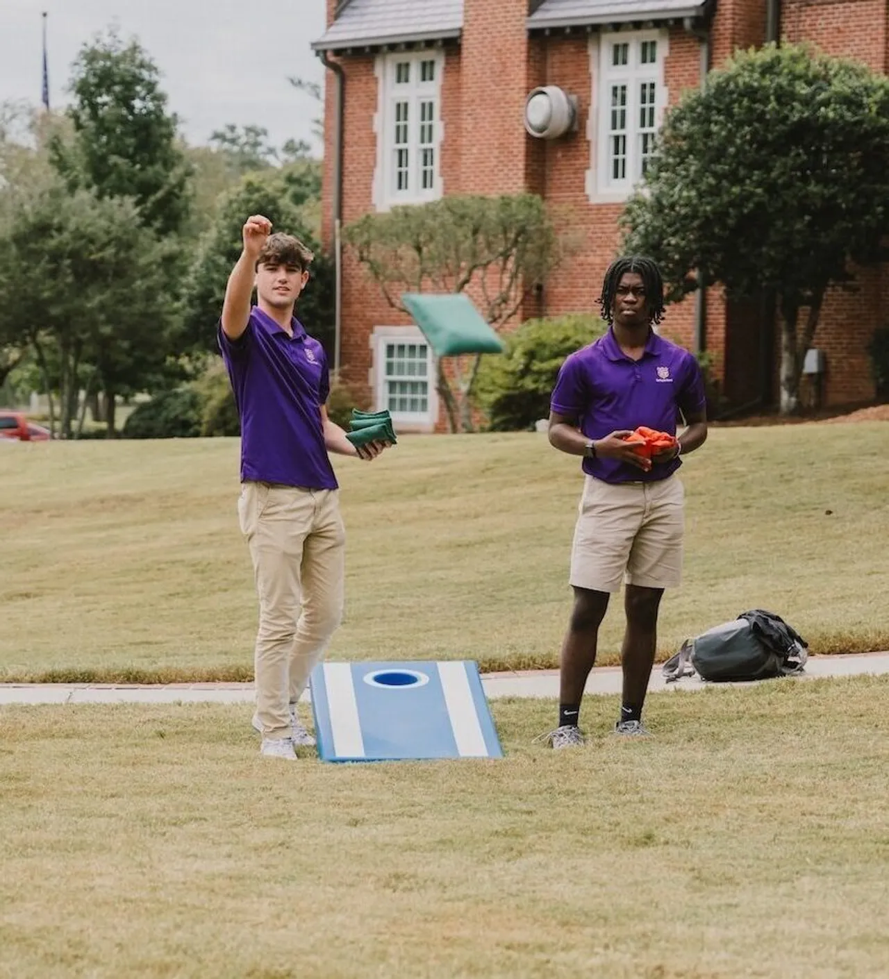 Two high school boys play cornhole on the Chapel Lawn at Darlington School