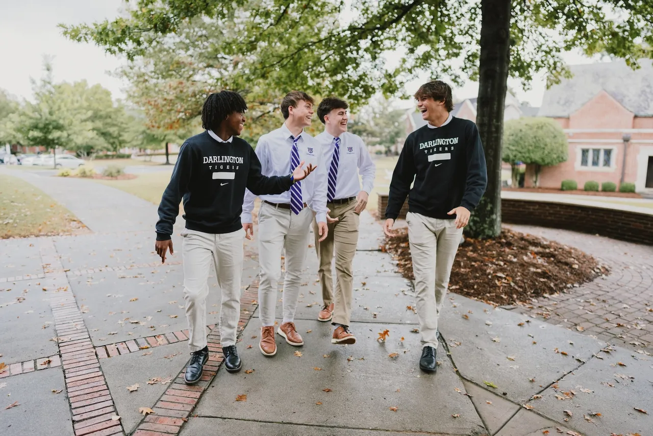 Four male students walking together and talking on the Darlington School campus.