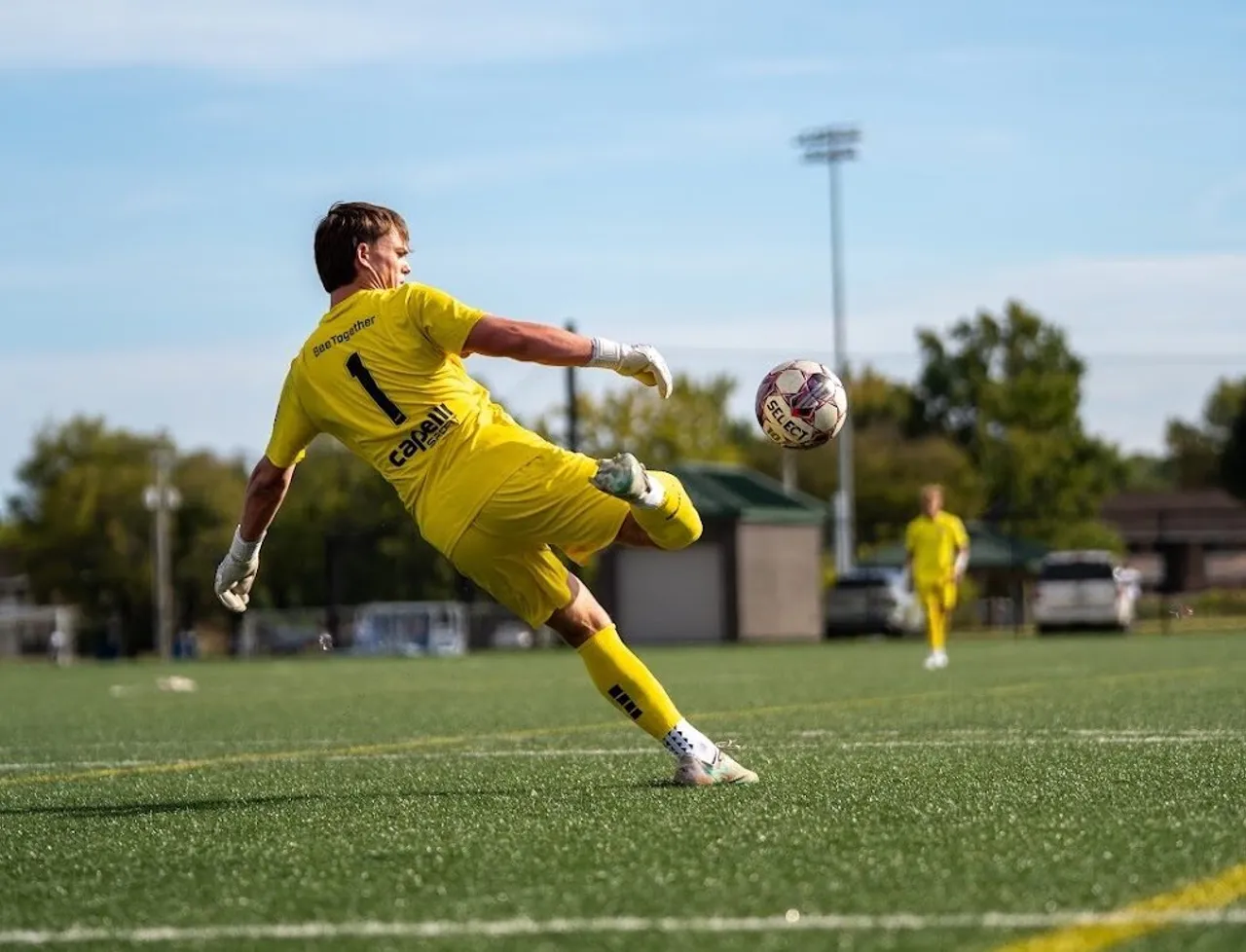 A soccer player in a yellow uniform kicks the soccer ball