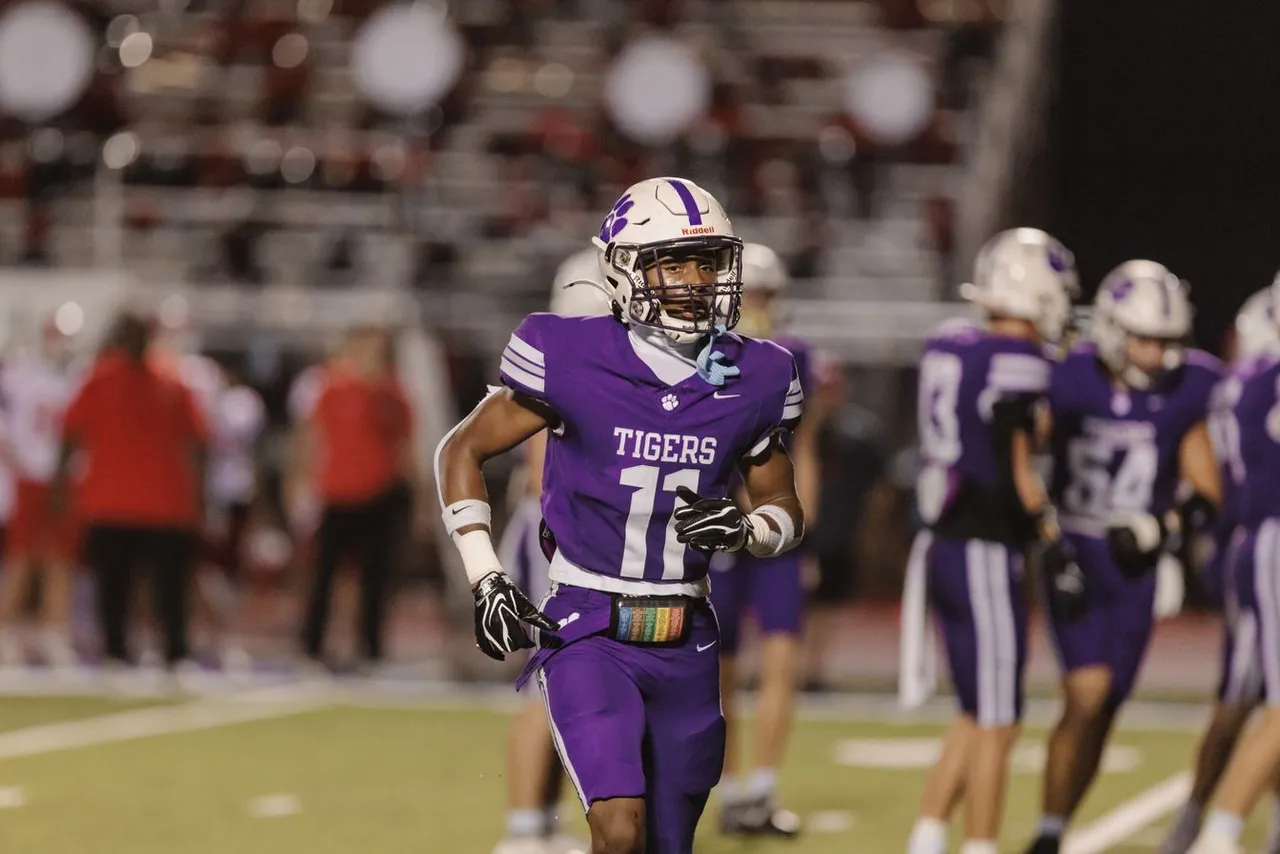A high school football player runs down the field during a football game.
