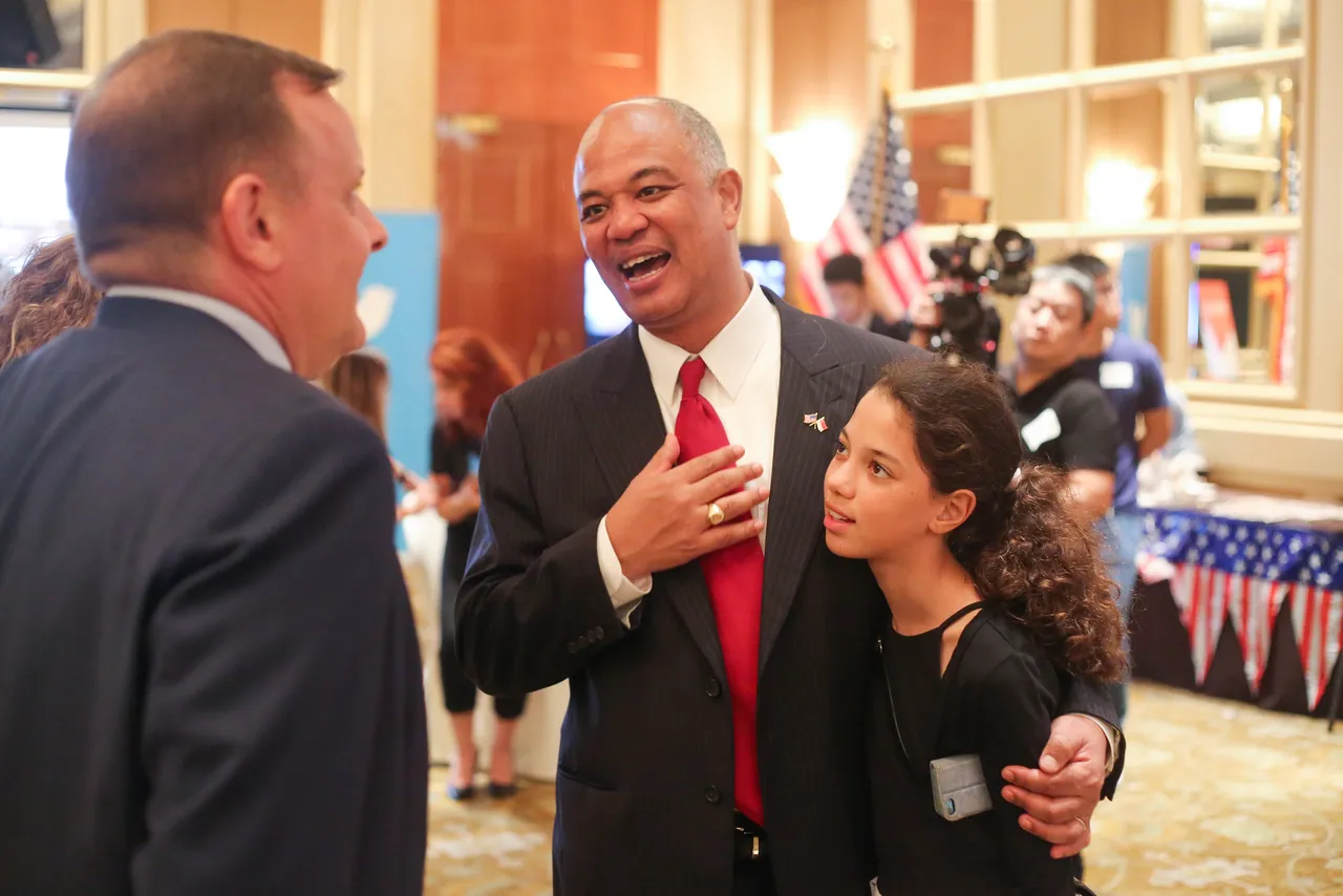 Darlington trustee Dwight Hutchins smiles while speaking with someone and standing with his arm around his daughter.