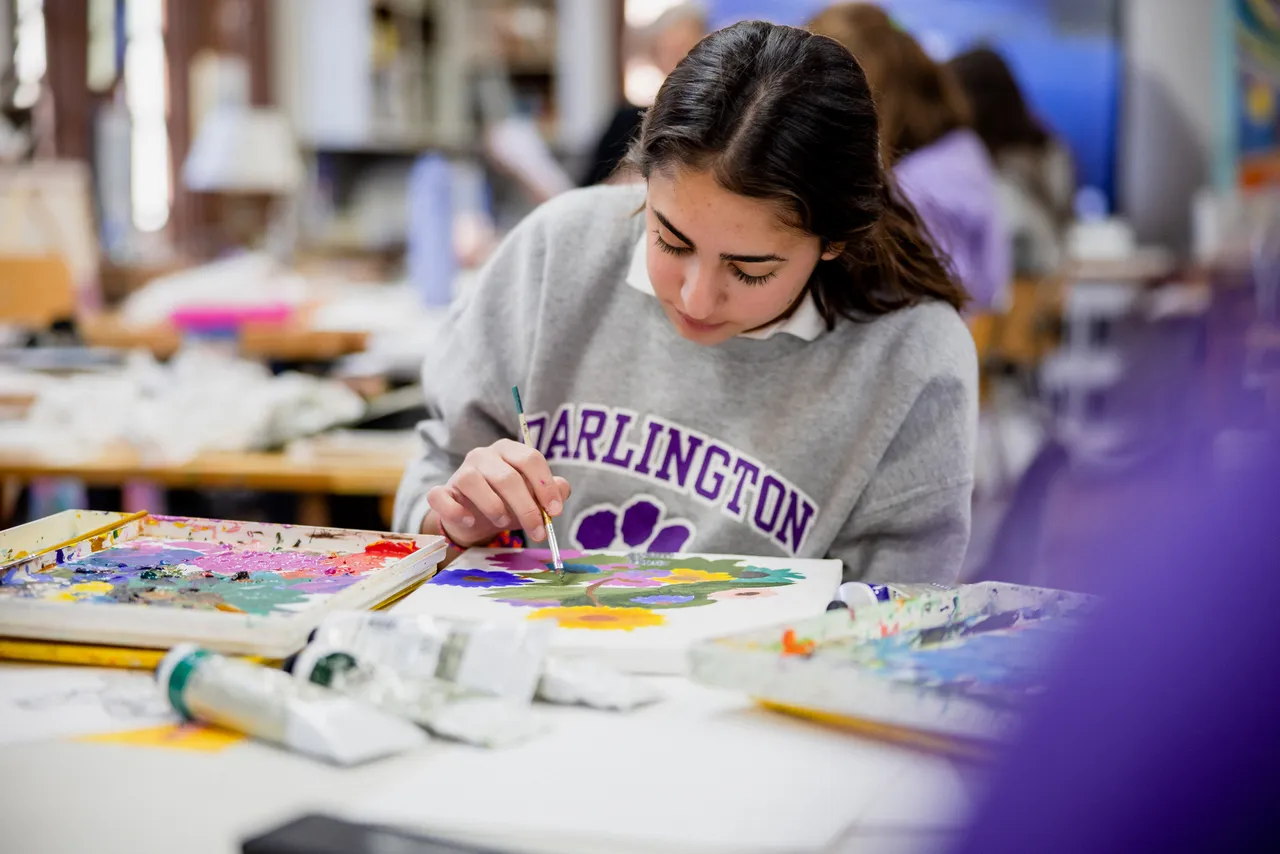 A female high school student paints during art class
