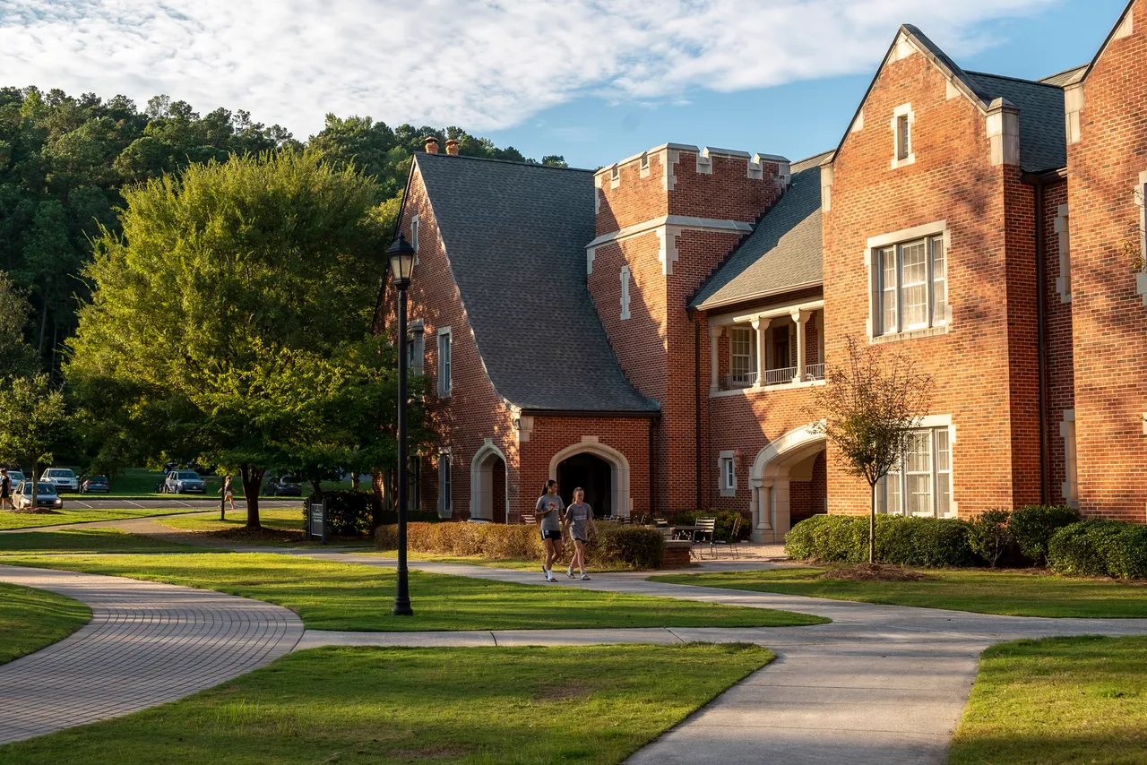 Two female students walk beside Thornwood Hall on Darlington School's campus.