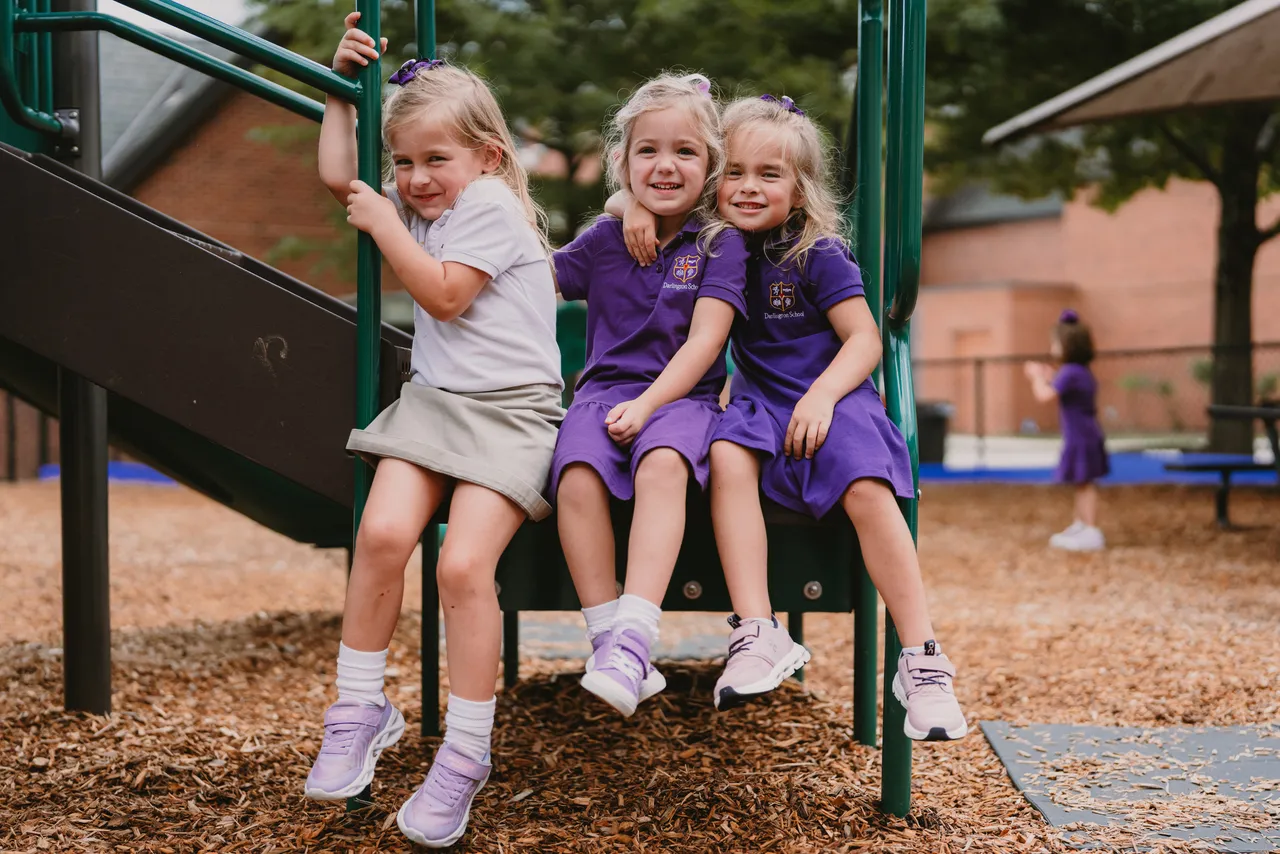 Three female primary grades students play on the playground during recess