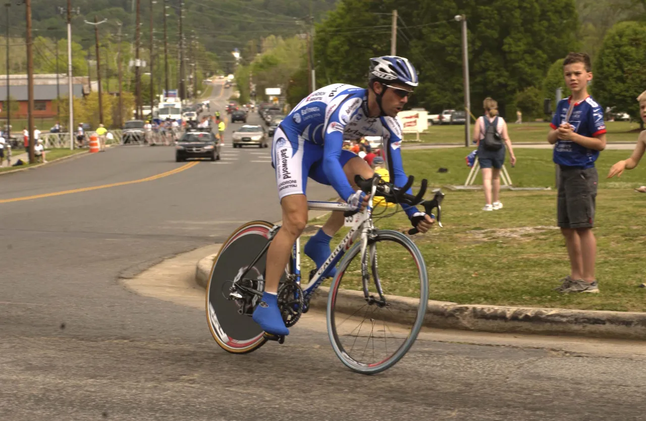 A rider takes the turn at Darlington Drive and Cave Spring Road in front of the main entrance to the School at the start of his time trial.