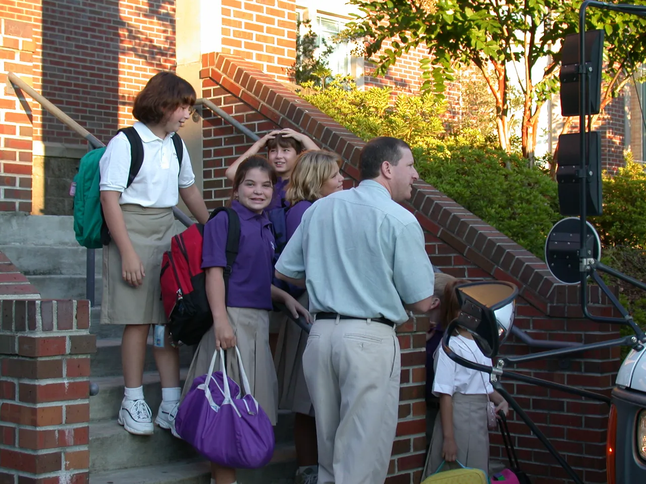 Faculty children, on the Upper School Library steps, wait for the bus to take them (in uniform) to the Lower School.