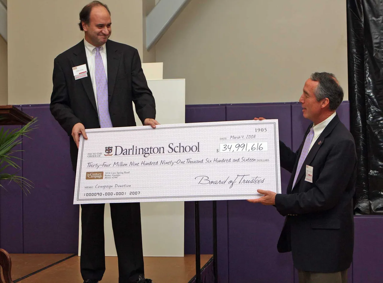 Board Chairman John Irby ('81) presents Headmaster Tom Whitworth with a symbolic check for $34,991,616 from the Board of Trustees.