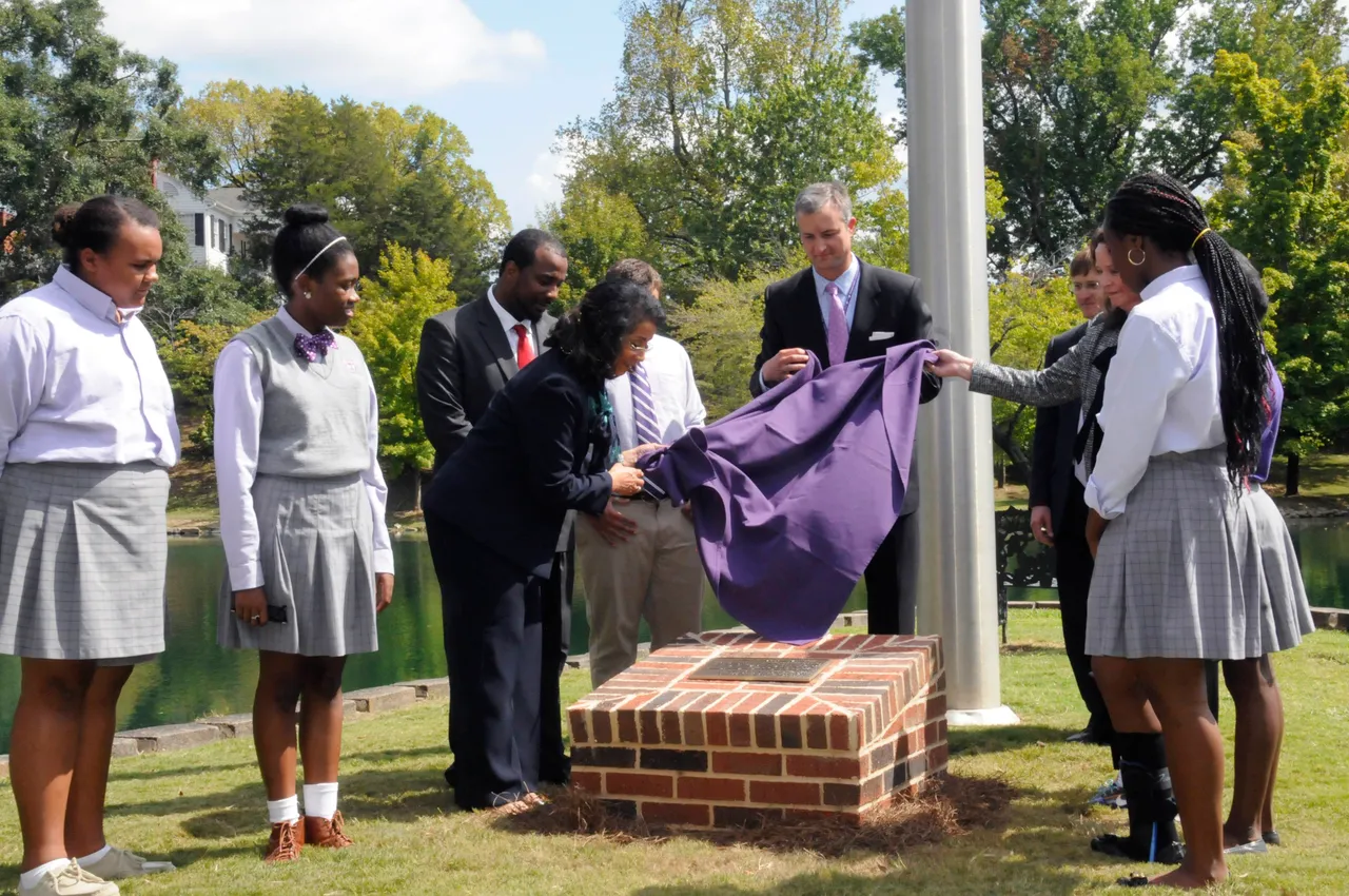 With help from Head of School Brent Bell and Board of Trustees Chair Linda (Grizzard) Owens ('79), Carmento Floyd (center) unveils a new bronze plaque in honor of her late husband at Dr. Elson S. Floyd ('74) Legacy Point.