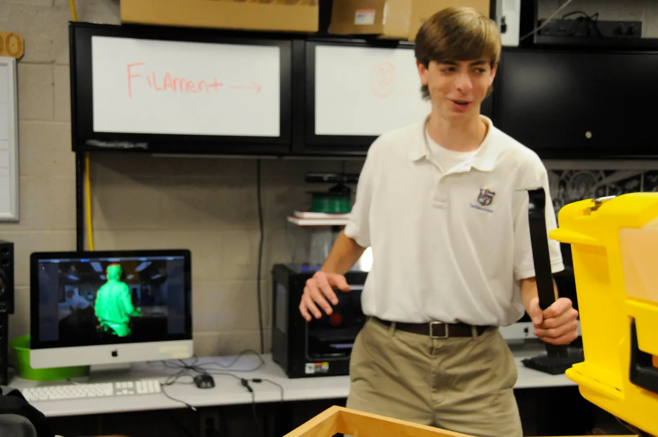 Junior Cooper Brock stands still on a revolving platform while a 3-D digital rendering is created of his body.