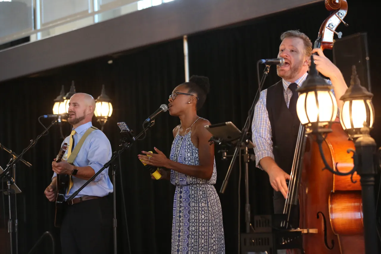 Acoustic trio Lilac Wine performs as attendees visit with one another and browse the silent auction items.