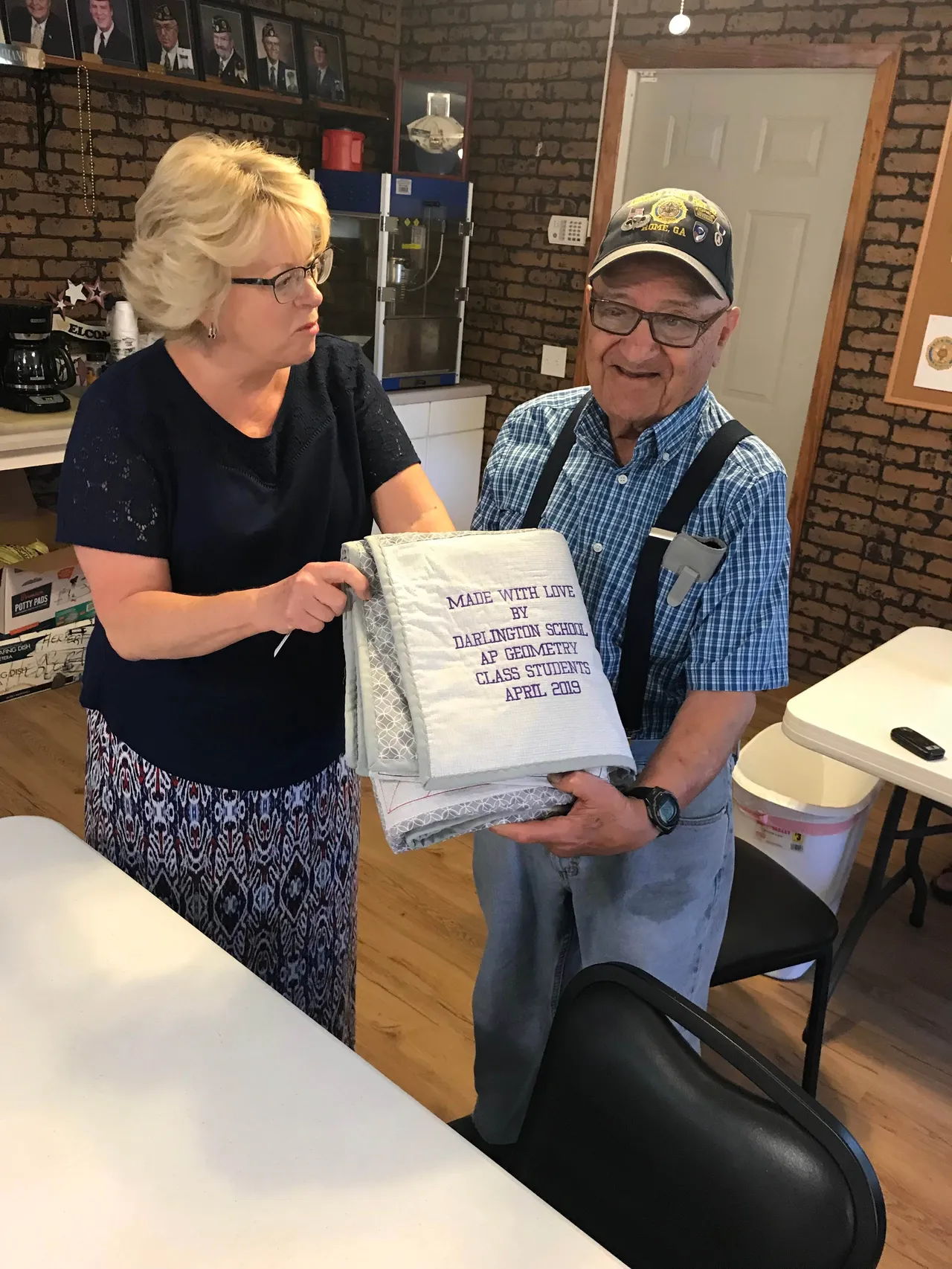 Penne Baldwin, Regent of the Xavier Chapter of the Daughters of the American Revolution, presents the quilt to Abraham Rodriguez.