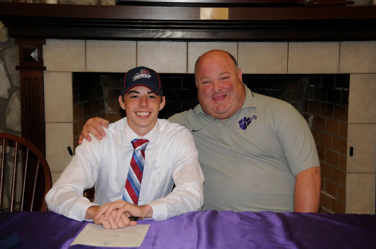 Head of House John Zazzaro celebrates with one of his house residents at a college signing.