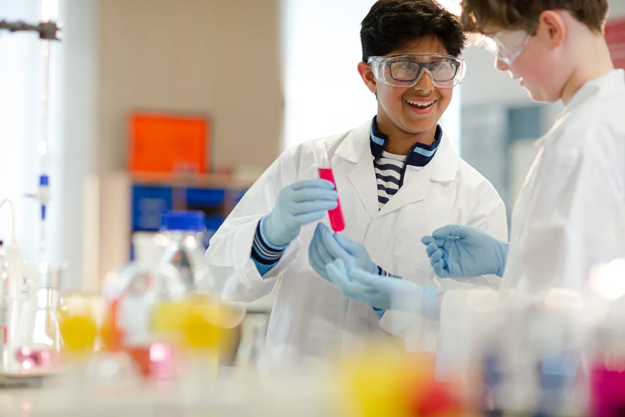 Middle School Student in lab coat holding test tub